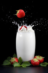 Strawberries splashing into milk