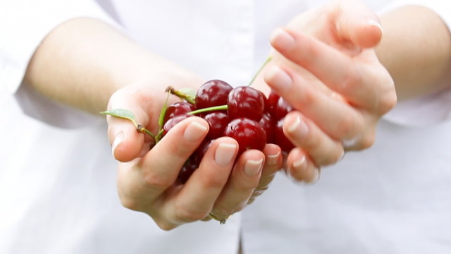 Cherry fruis in woman's hands. Manicure professionally done.