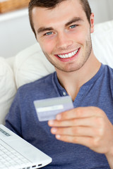 Close-up of a jolly man holding a card and a laptop