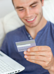 Close-up of a smiling man holding a card and a laptop