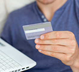 Close-up of a caucasian man holding a card and a laptop