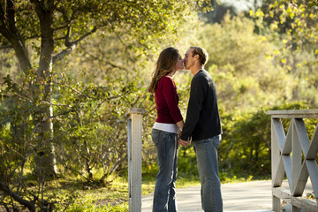 Caucasian couple kissing on outdoor wooden bridge