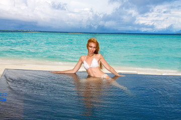 Young pretty woman in the pool and ocean . Maldives