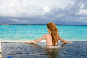 Young pretty woman in the pool and ocean. Maldives..