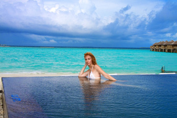 Young pretty woman in the pool and ocean . Maldives..