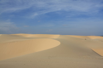 Dünenlandschaft mit weißem Sand vor blauem Himmel