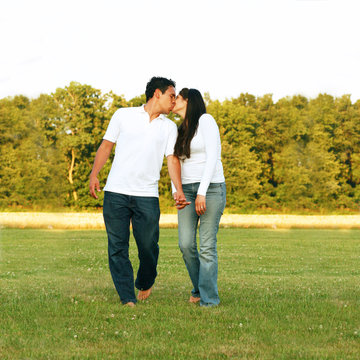 Young couple walking and kissing at the park
