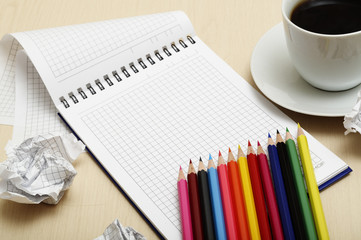 Coffee cup and spiral notebook and pen on the wooden table