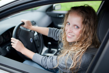 Obraz na płótnie Canvas Pretty young woman driving her new car