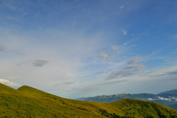 Cloudy blue sky upon green mountains