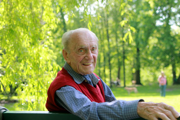 Alter Mann auf Bank im Grünen - lachend