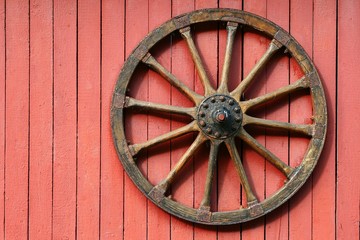 Holzrad an einer roten Wand einer Scheune