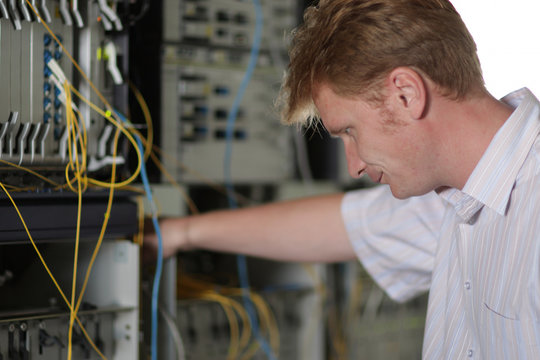 Telecom engineer looks on multiplexer