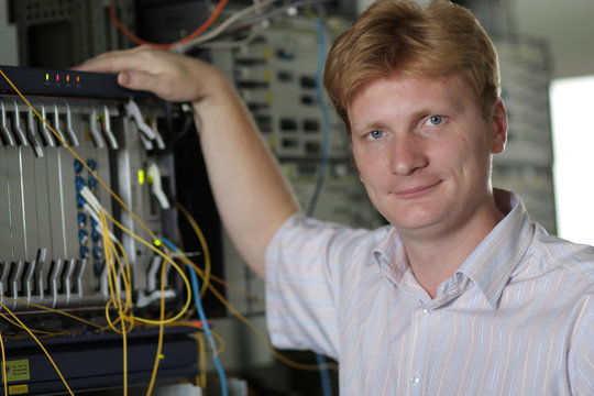 Telecom engineer poses on multiplexer background