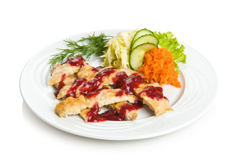 Sliced pork chop with cowberry sauce and vegetable side dish.