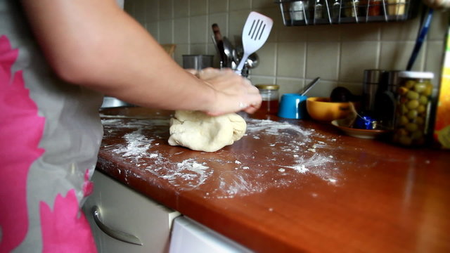 Female hands in flour closeup kneading dough on table
