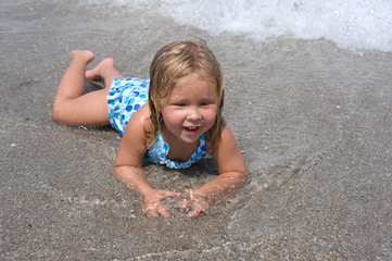 Adorable little blond girl at the beach in the ocean