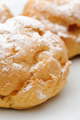 Three profiteroles on a plate, isolated, white background