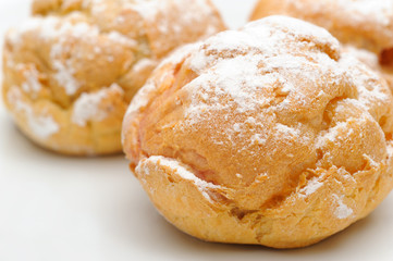 Three profiteroles on a plate, isolated, white background