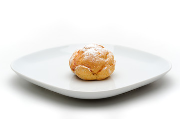 Single profiterole on a plate, isolated, white background