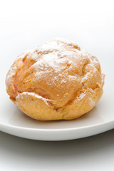 Single profiterole on a plate, isolated, white background