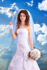 Beautiful woman with in wedding dress over blue sky background