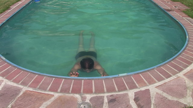 Junger Mann steigt aus dem Swimmingpool