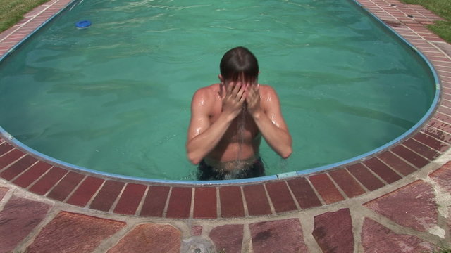Junger Mann steigt aus dem Swimmingpool