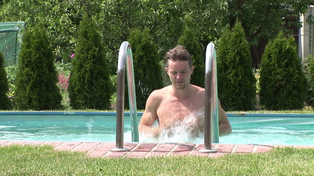 Junger Mann steigt aus dem Swimmingpool