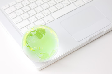 緑色に発光する地球儀と白いノートパソコン