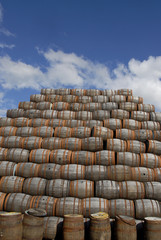 Barrels with rusted metal rings in a yard, pilled up.