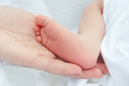 Mothers hand holding her newborn baby feet