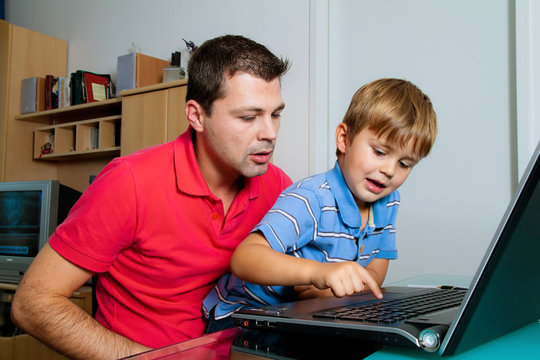 Mann und Kind mit Laptop Computer in Wohnung.