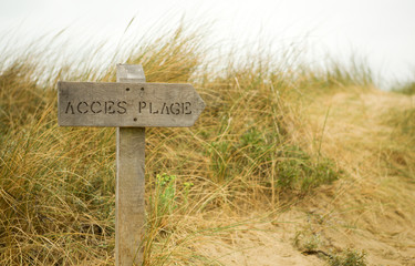 Way to the beach. Wooden signpost with indication in French