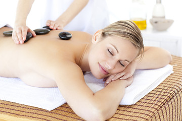 Obraz na płótnie Canvas Pretty young woman receiving a massage with hot stone