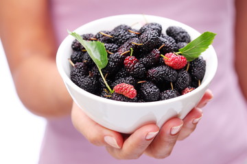 Crockery with mulberries in woman hand.