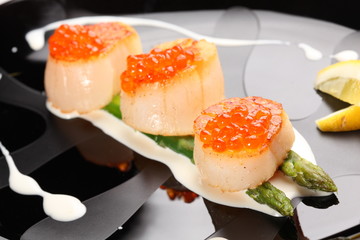 Grilled sea scallops with asparagus in a black plate
