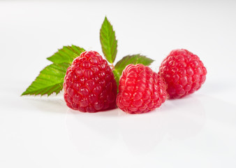trois belles framboises sur fond blanc avec leurs feuilles