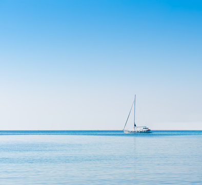 Sailboat in Adriatic sea. Blue sky over water horizon. Copyspace