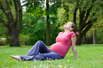 Naklejka na ściany i meble Beautiful pregnant woman relaxing in the park