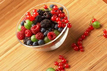 Fruit mix in the glass container, on a table from straw