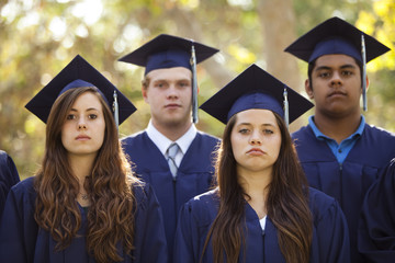 Graduating students in caps and gowns with serious faces