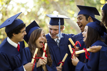 Graduating students smiling and laughing with diplomas