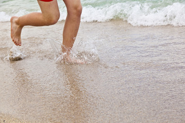 feet of boy running along the beach