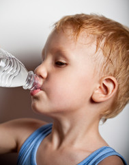 Quench thirst. The boy is drinking mineral water from bottle