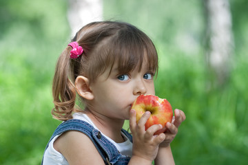 Little girl portrait eating red apple outdoor