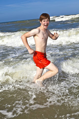 Fototapeta na wymiar boy running through the water at the beach