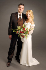 Portrait of the young happy newlyweds on dark background