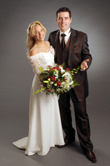 Portrait of the young happy newlyweds on dark background
