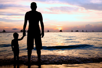 father and son on sunset sea background